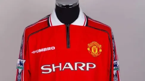 Beckham's red Man Utd shirt, with SHARP on the front in white letters, and the Premier League badge and Umbro logo on the long sleaves, hangs on a clothes horse