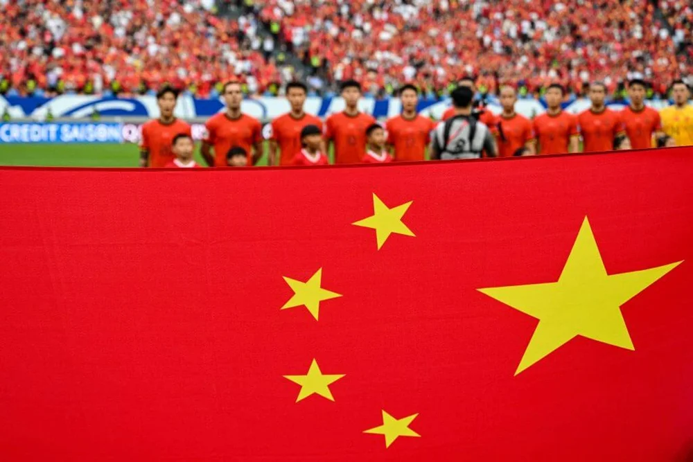 China's players sing the national anthem as they stand behind the country's national flag